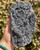 Black Amethyst cluster from Artigas, Uruguay held in hand outdoors, showing sparkling purple-gray druzy crystals