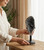 Woman setting a Black Amethyst cluster on its iron stand onto a wooden table