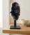 Black Amethyst cluster on its iron stand on a wooden table beside a small bowl and a sage bundle