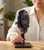 Hand setting a Black Amethyst cluster on its iron stand onto a wooden table