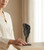 Woman resting her hand beside a Black Amethyst cluster on its iron stand on a wooden table