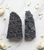 Two raw Black Amethyst geodes on white marble surrounded by dried white rose petals
