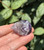 Amethyst sleeping cat figurine held in hand, showing white chevron markings across its curled back