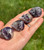 Four small Amethyst cat carvings curled up asleep in a palm outdoors