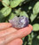 Amethyst sleeping cat carving with pale lavender ears and purple banded body held in hand