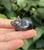 Polished Smoky Quartz sleeping cat carving from Brazil held on fingertips, showing translucent smoky gray tones