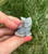 Pale Labradorite sitting cat with soft blue flash and dark inclusions, held in hand outdoors