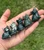 Five Moss Agate sitting cat carvings in a palm, showing the natural range from dark green to speckled white and green