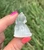 Side view of a Clear Quartz sitting cat carving held between fingertips outdoors