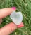 Back of a Clear Quartz sitting cat carving held between fingers, showing natural internal clouds