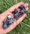Five Amethyst sitting cat carvings in an open hand, ranging from deep violet to banded purple and white
