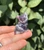 Front view of an Amethyst sitting cat with carved eyes and pointed lavender ears, held in hand