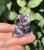Close-up of an Amethyst sitting cat showing its carved face and soft purple and white chevron markings