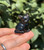 Smoky Quartz sitting cat held in hand against green leaves, about 1.25 inches tall, with carved eyes and ears