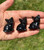 Three polished Smoky Quartz cats sitting in a row in a palm, near-black with a soft smoky glow