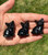 Three small Smoky Quartz cat figurines lined up in hand in the sunlight