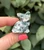 Polished Tree Agate sitting cat carving from Botswana held between fingers, white with green dendrite patterns
