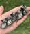 Five Pyrite sitting cat carvings lined up in a palm, from heavy gold sparkle to mostly black stone
