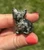Side view of a Pyrite sitting cat held between fingers, with brassy gold patches on a black body