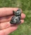 Pyrite sitting cat with gold flecks catching the sunlight, held between fingers outdoors
