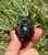 Silver Sheen Obsidian owl held between fingers, its polished black body catching a silver glow