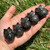 Row of five Silver Sheen Obsidian owls in an open hand in the sunlight
