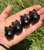 Four Smoky Quartz owl carvings in a palm, ranging from smoky gray to near-black