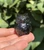 Smoky Quartz owl held in hand against green leaves, about 1.25 inches tall, with translucent smoky tones