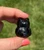Back of a Smoky Quartz owl carving held between fingertips, showing its glossy dark finish