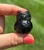 Smoky Quartz owl held between fingers, with light catching its smoky ears and face