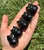 Five Black Obsidian owl carvings lined up in a palm, each with a mirror-like black shine