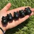 Five small Black Obsidian owls resting in a hand in the sunlight