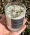 Hand holding Winter crystal candle outdoors, black label reading All Natural Candles, crystals and herbs on the white wax
