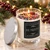 Lit Be Merry crystal candle with silver lid among evergreen branches, red berries and twinkling holiday lights