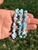 Hand holding three light blue Larimar chip elastic bracelets over green grass