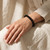 Black Obsidian bracelet worn on a wrist with the hand resting on a cream linen lap