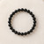 Top view of a Black Obsidian round bead bracelet on a white textured surface