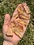 Palm holding several raw copal amber pieces in sunlight above green grass