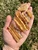 Raw copal amber pieces held in a hand outdoors, sunlight glowing through the golden resin