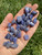 Tanzanite Tumbled Stones in hand showing deep violet-blue color, white veining and natural inclusions