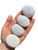 Hand holding four polished Scolecite palm stones showing their silky white fibrous texture