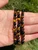Two Empath Protection Bracelets held in an open palm outdoors showing golden Tiger's Eye, smoky brown quartz and black tourmaline beads