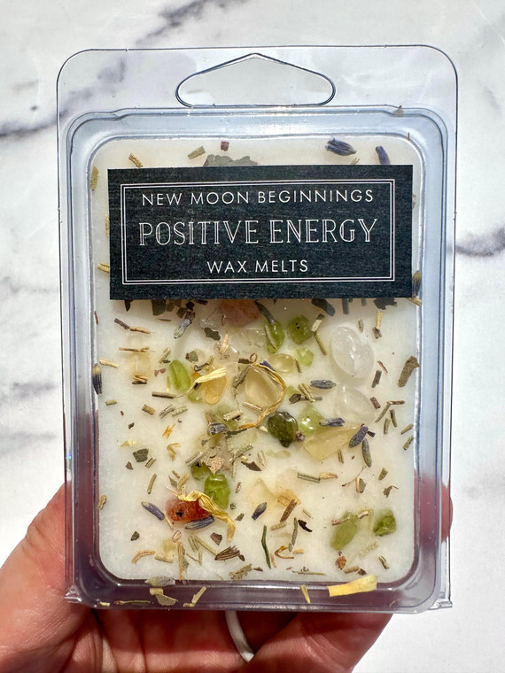 Hand holding Positive Energy Wax Melts by New Moon Beginnings, cream soy wax topped with Citrine, Peridot, Sunstone and Clear Quartz chips, lavender and rosemary