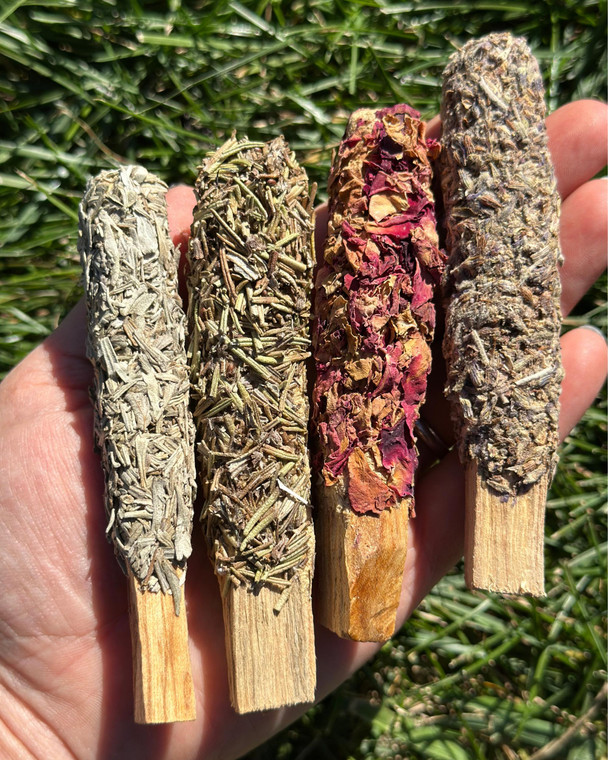 Dipped Palo Santo Stick Four Pack with blue sage, rosemary, rose and lavender sticks held in a hand outdoors