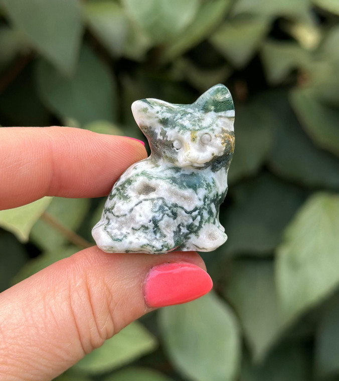 Polished Tree Agate sitting cat carving from Botswana held between fingers, white with green dendrite patterns