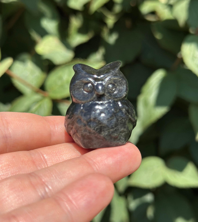 Polished Silver Sheen Obsidian owl carving from Mexico held in hand, with a silvery shimmer across its carved feathers