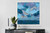 Atmospheric abstract seascape canvas wall art by Shakia Harris featuring layered shades of deep blue, teal, lavender, aqua, and soft cloud-like movement above a tranquil horizon line. This expressive coastal-inspired canvas print is displayed in a modern neutral interior and highlights premium features including water-resistant protection, fade-resistant archival inks, and a textured canvas finish. The moody ocean tones and impressionistic brushwork create a calming, immersive atmosphere ideal for living rooms, bedrooms, offices, and modern coastal interiors. Designed to bring depth, serenity, and sophisticated color into contemporary spaces.