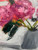 Close-up detail of Funny How Time Flies showing layered peony petals, deep botanical greens, and unexpected coral and orange accents.