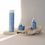 Three Phytomer skincare products in blue packaging displayed on natural stone and cream-colored blocks in minimalist setting