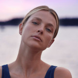 Woman stretching her neck at the beach during sunset.